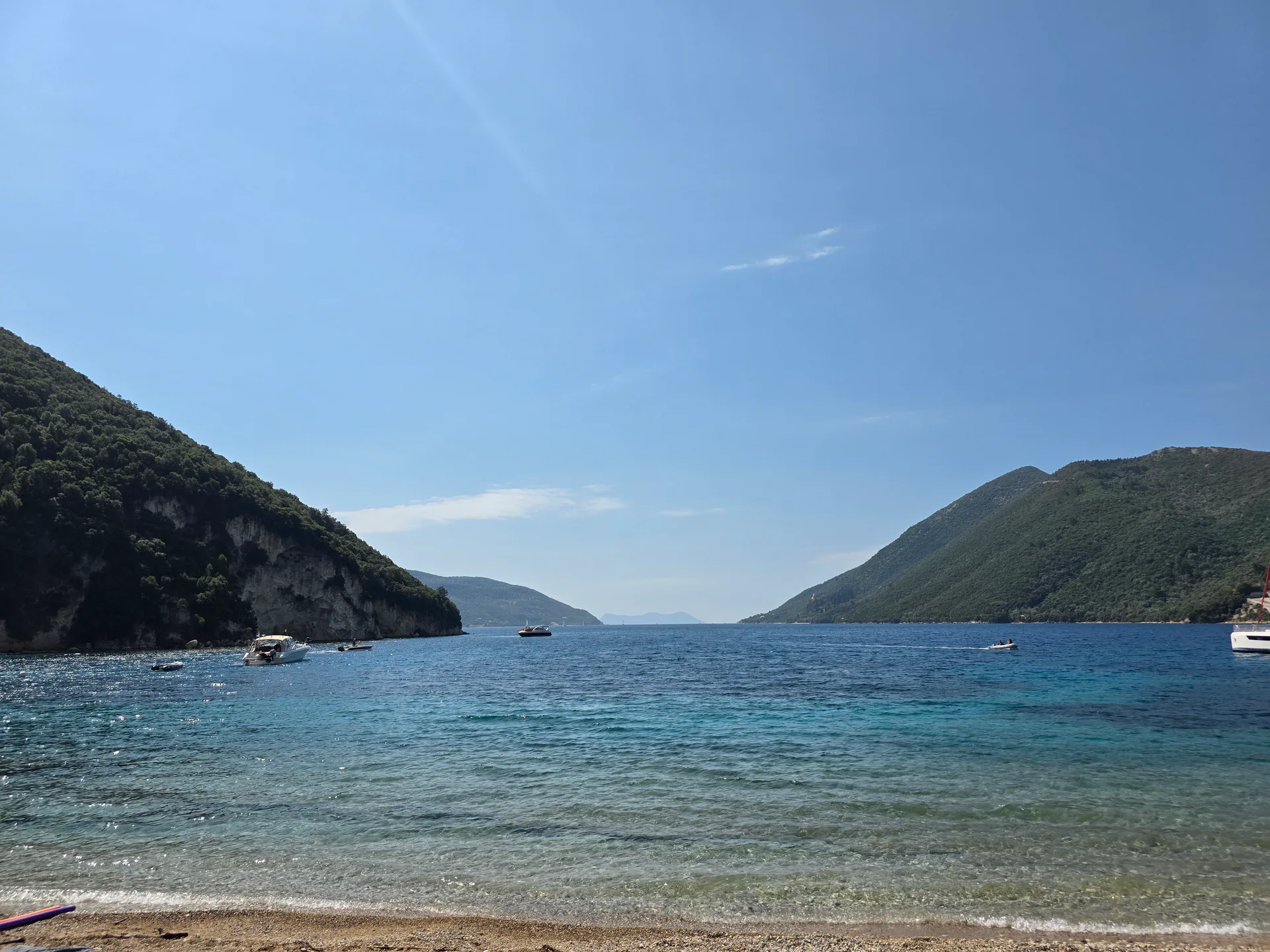 Clear Ionian water and green hills at Desimi Beach near Geni, Lefkada